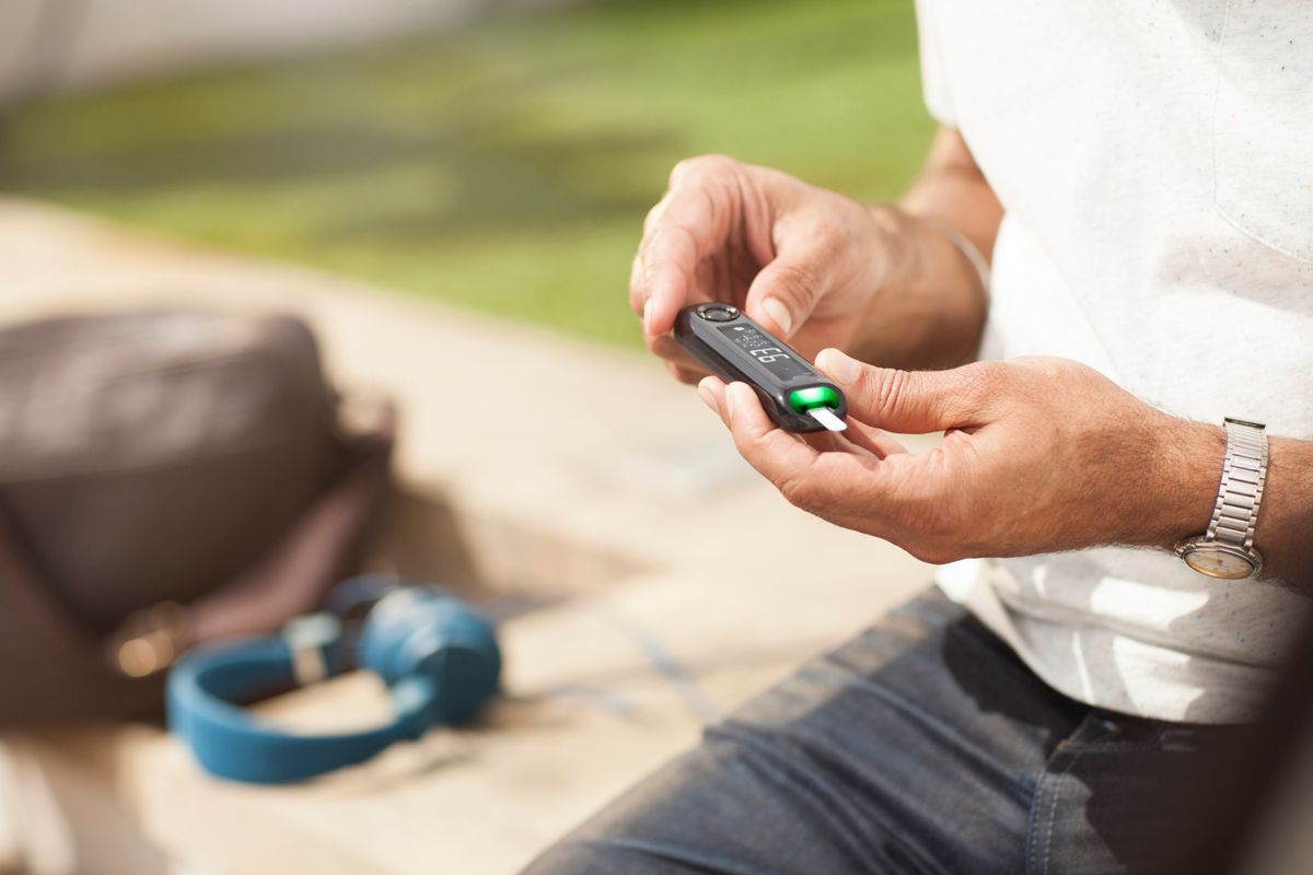 A person examines their blood glucose monitor reading Blood glucose monitor